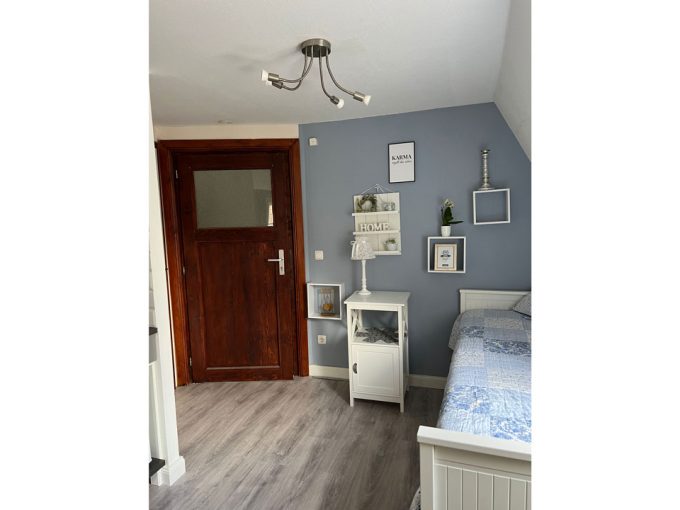 Ein kleines Schlafzimmer mit blauen Wänden und einer Holztür.