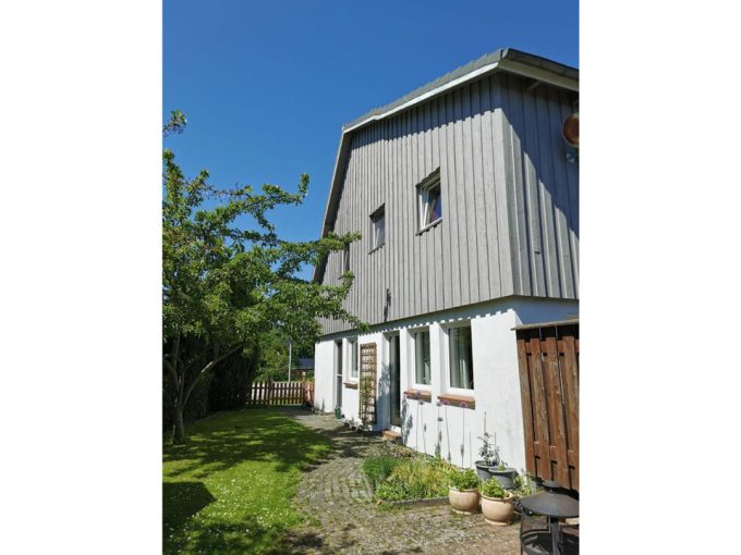 Ein Haus mit einer grauen Fassade und einer Holzterrasse.