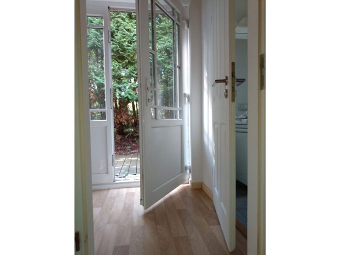 Eine Tür führt in einen Raum mit Holzboden.