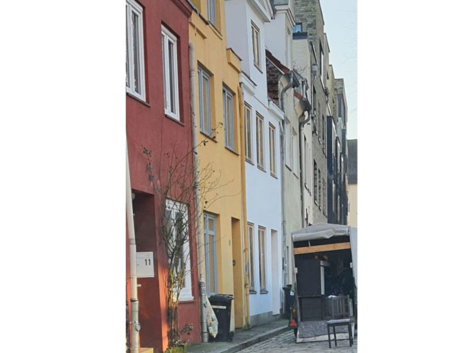 Ein Bus parkt vor einer Reihe bunter Gebäude.